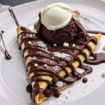 Serving chocolate drizzled crepe with ice cream
